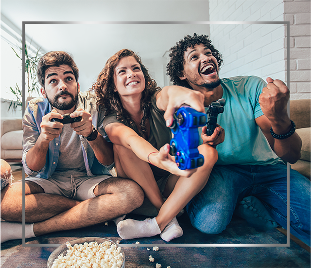 Un groupe de jeunes gens assis par terre joue aux jeux vidéo, satisfait après le traitement d’une mycose cutanée par Canesten®.