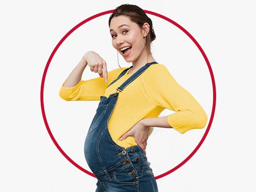 Une jeune femme enceinte, joyeuse et vêtue d'un pull jaune, montre son ventre