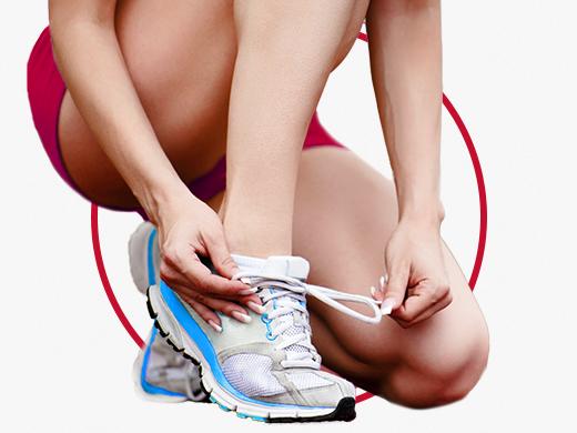 Frau in Shorts und weissen Sportschuhen beim Schuhe zubinden