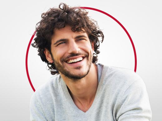 Jeune homme souriant portant un pull-over gris, satisfait après un traitement d’une mycose par Canesten