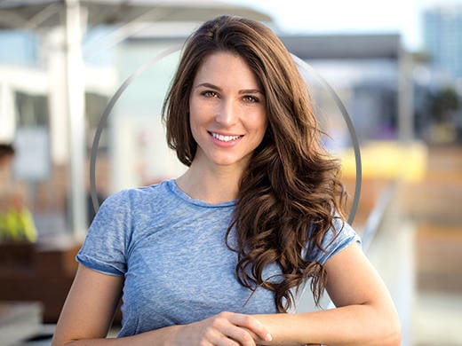 Une jeune femme brune souriante qui porte un T-shirt bleu réfléchit aux probiotiques.