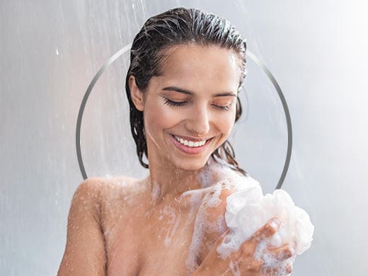 Jeune femme brune souriante qui prend sa douche