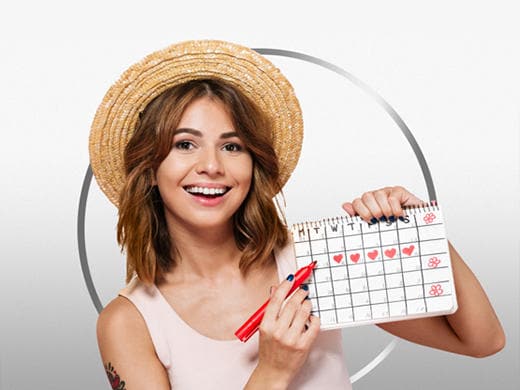 Lächelnde, braunhaarige junge Frau im hellen Shirt hält Kalender hoch