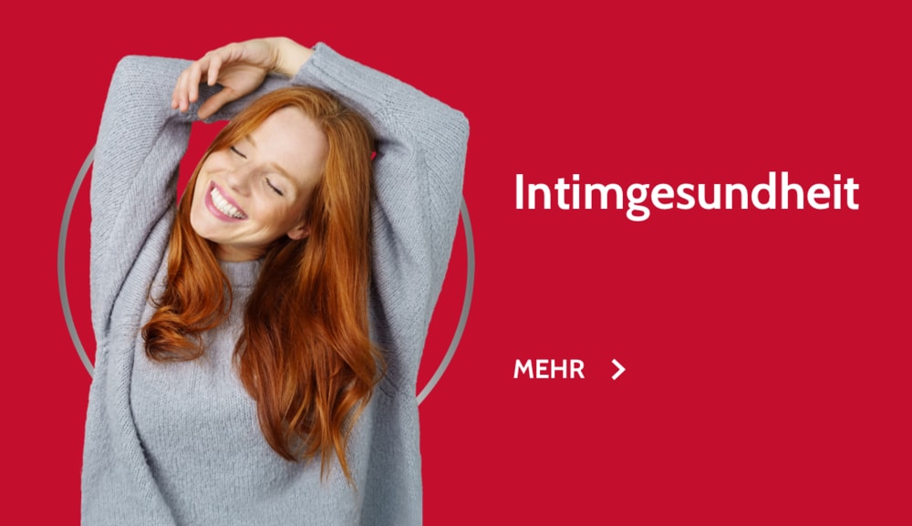 Glücklich lächelnde rothaarige junge Frau im pinkfarbenen Sweater
